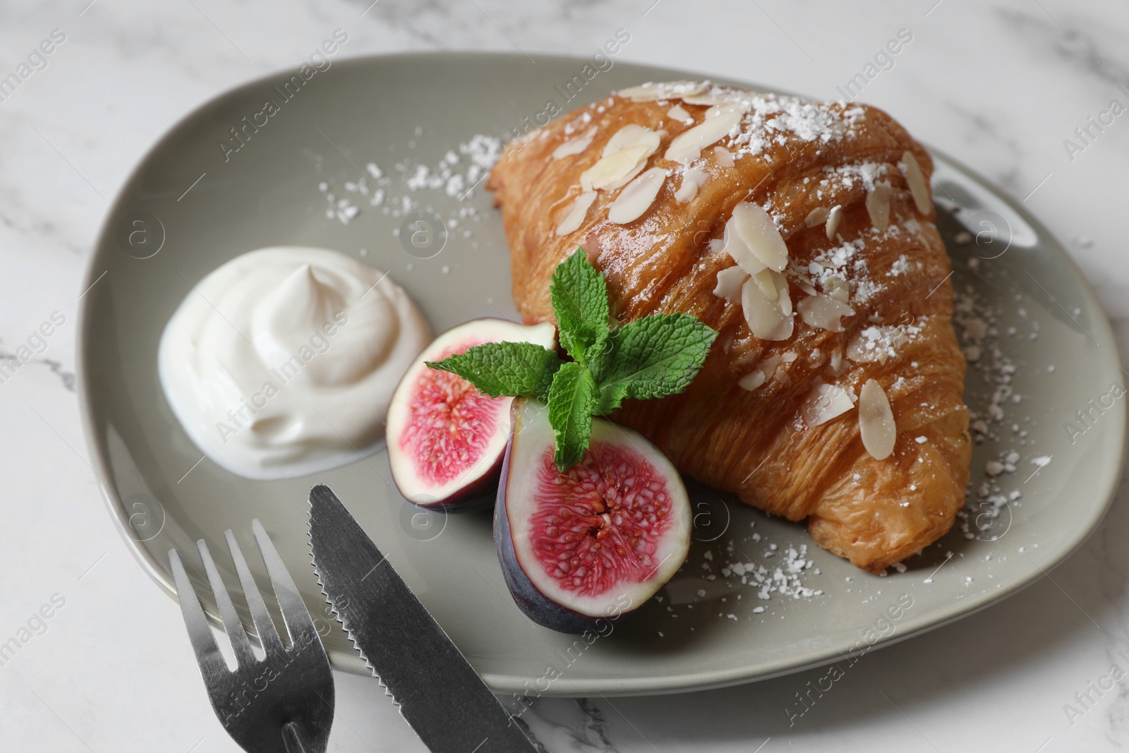 Photo of Delicious croissant with fig served on white marble table, closeup