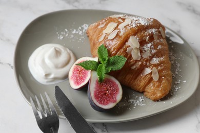 Delicious croissant with fig served on white marble table, closeup