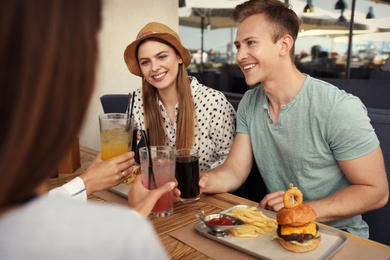 Photo of Young people with burgers in street cafe