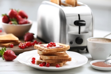 Tasty breakfast with toasted bread and fresh berries on white marble table in kitchen