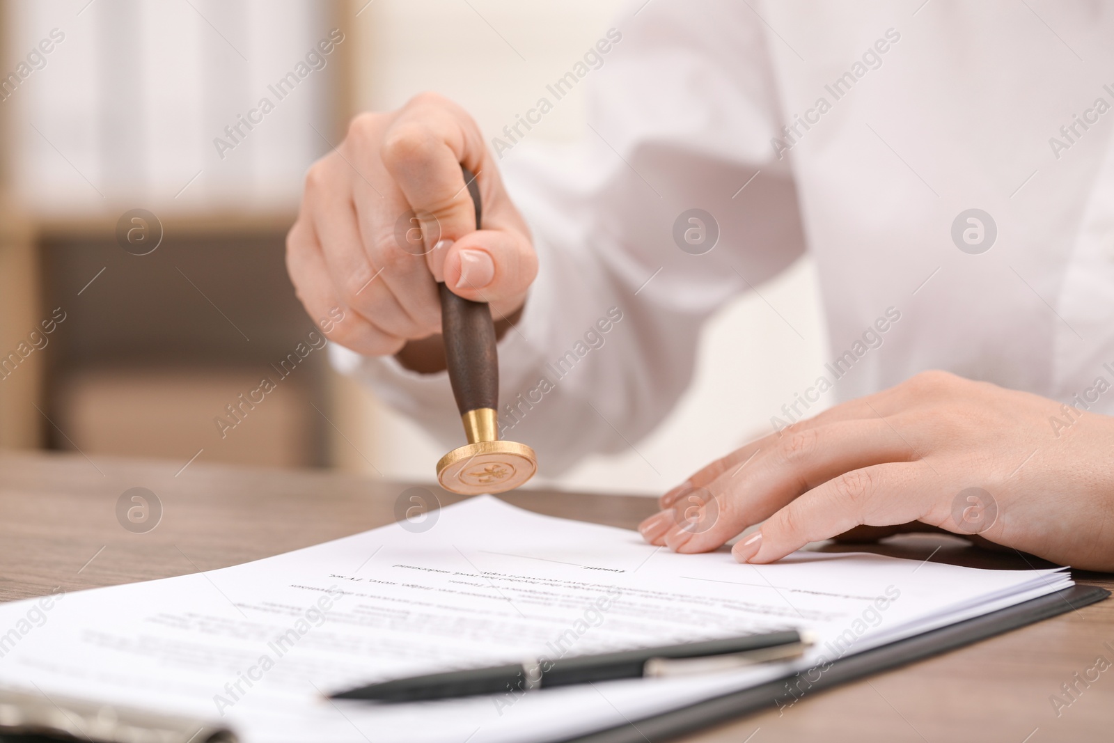 Photo of Woman stamping document at table, closeup view