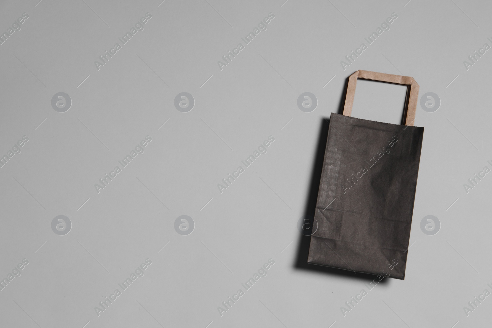 Photo of One black paper shopping bag on grey background, top view. Space for text