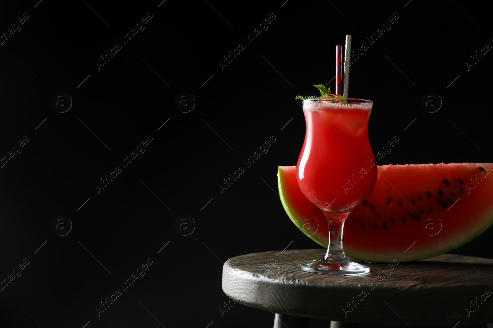 Photo of Tasty watermelon drink and fresh fruit on table against black background, space for text