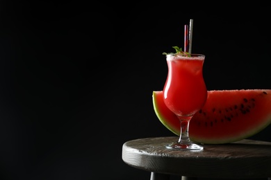 Photo of Tasty watermelon drink and fresh fruit on table against black background, space for text