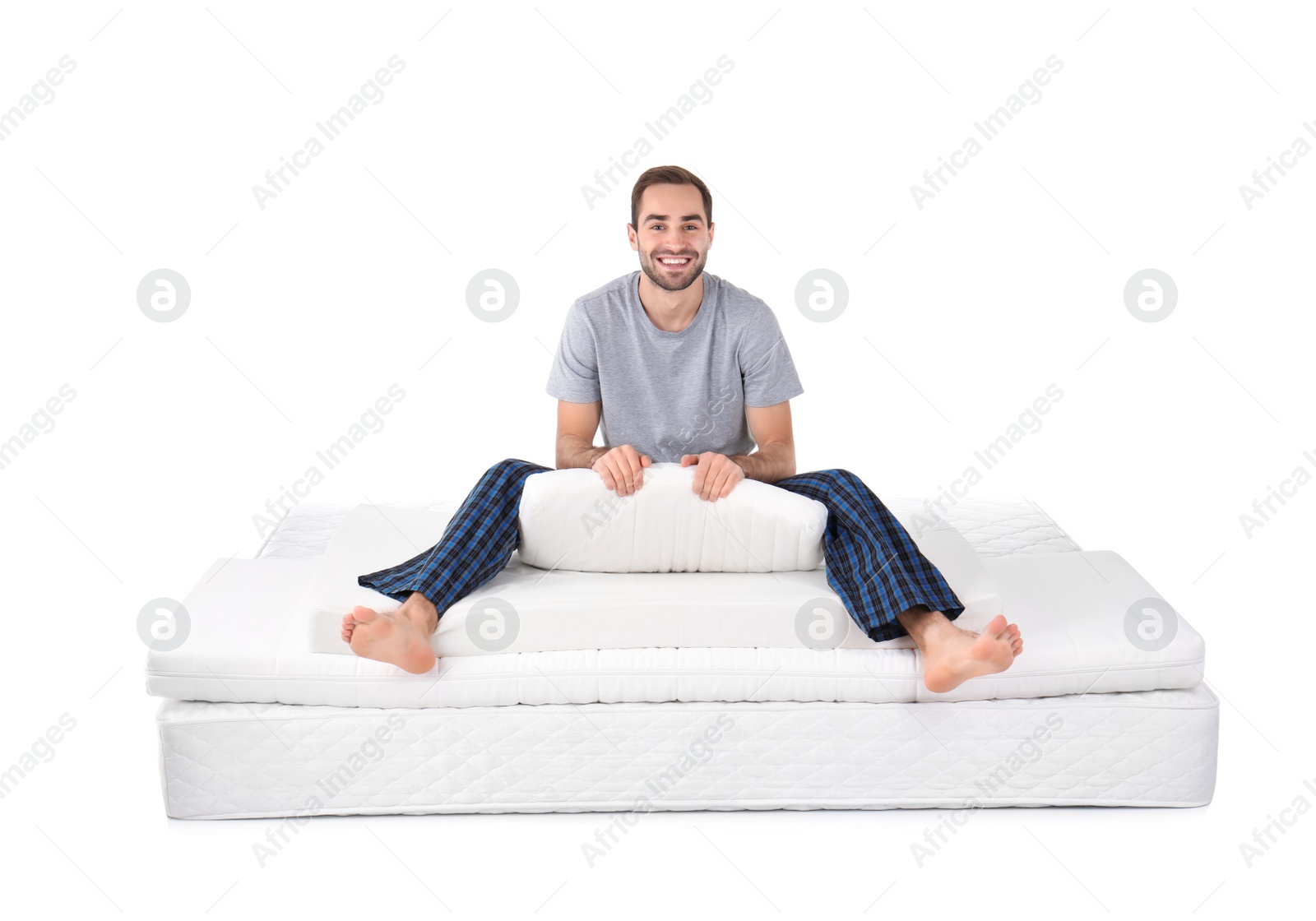 Photo of Young man sitting on mattress pile against white background