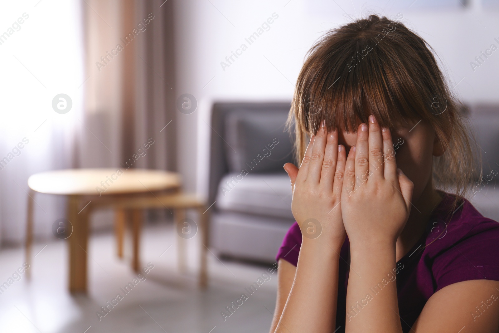 Photo of Abused little girl closing eyes indoors, space for text. Domestic violence concept