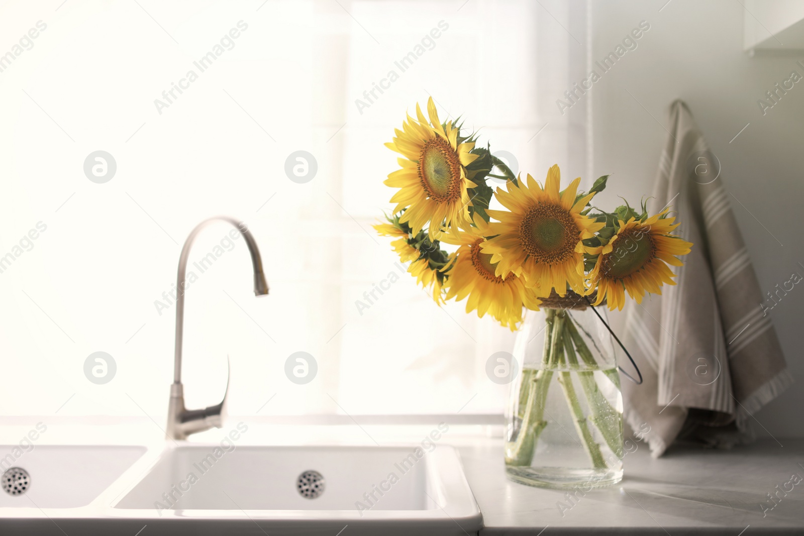 Photo of Vase with beautiful yellow sunflowers in kitchen
