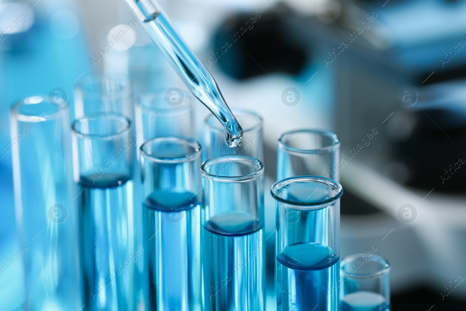 Photo of Dripping liquid from pipette into test tube in laboratory, closeup