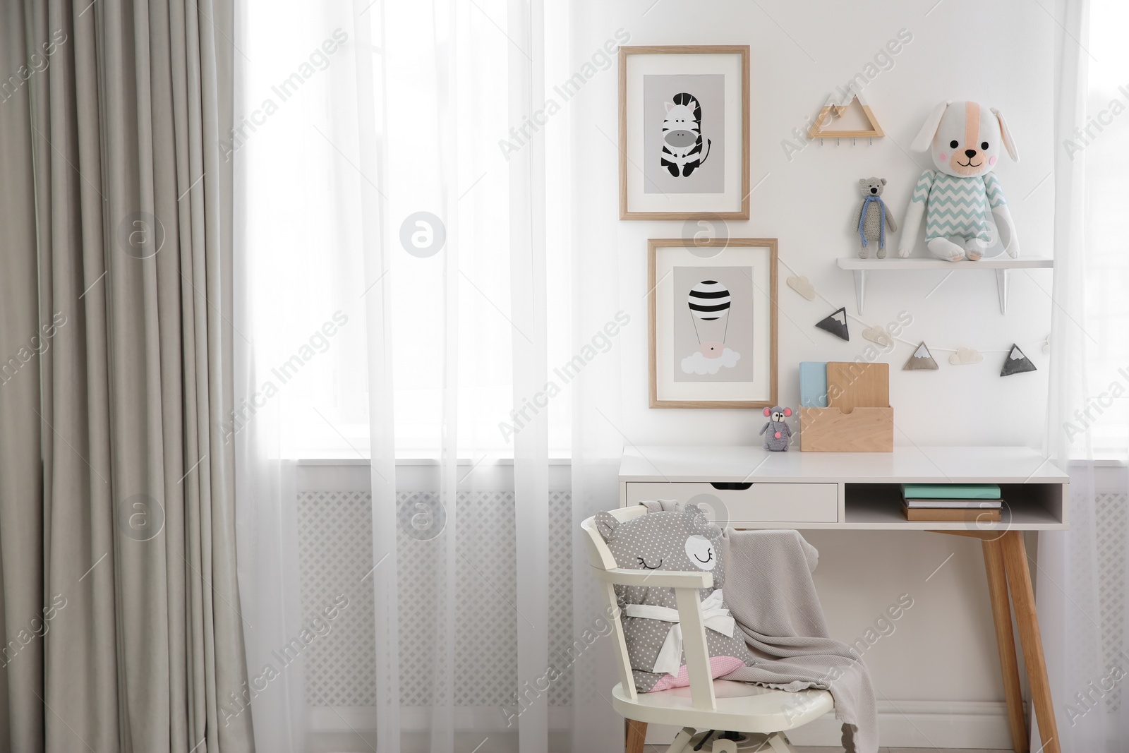 Photo of Stylish child's room interior with desk and beautiful pictures