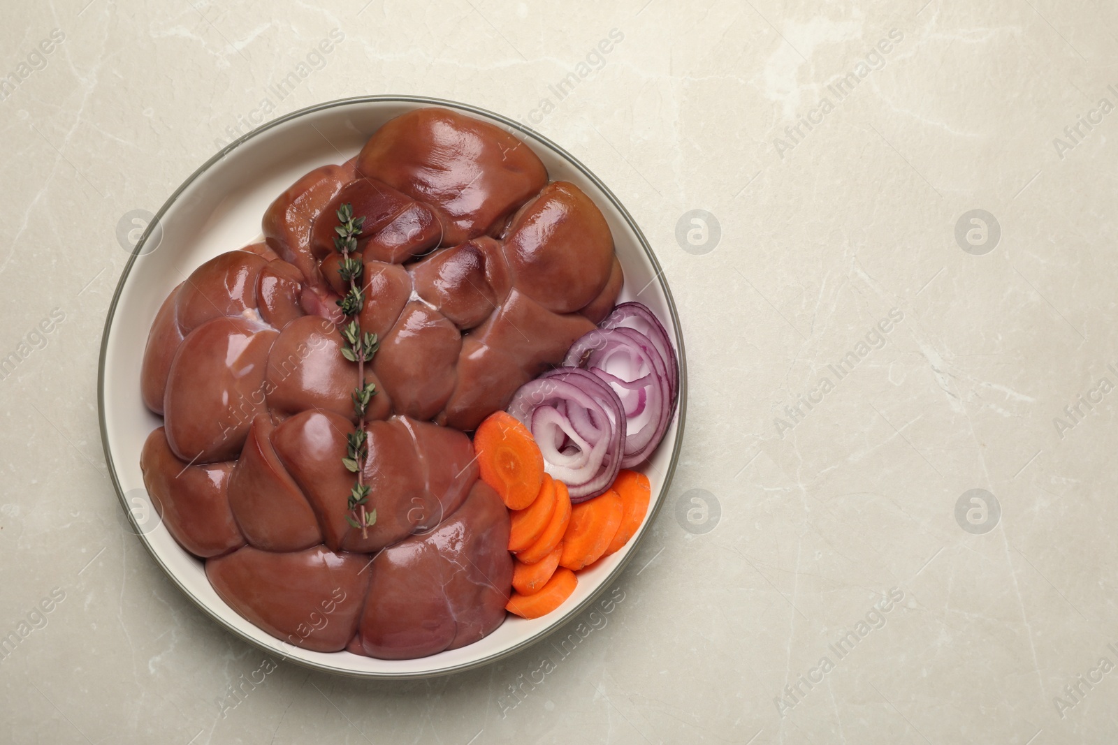Photo of Fresh raw kidney meat with vegetables on light grey table, top view. Space for text