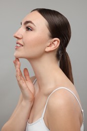 Photo of Smiling woman touching her chin on grey background