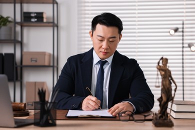 Notary writing notes at wooden table in office