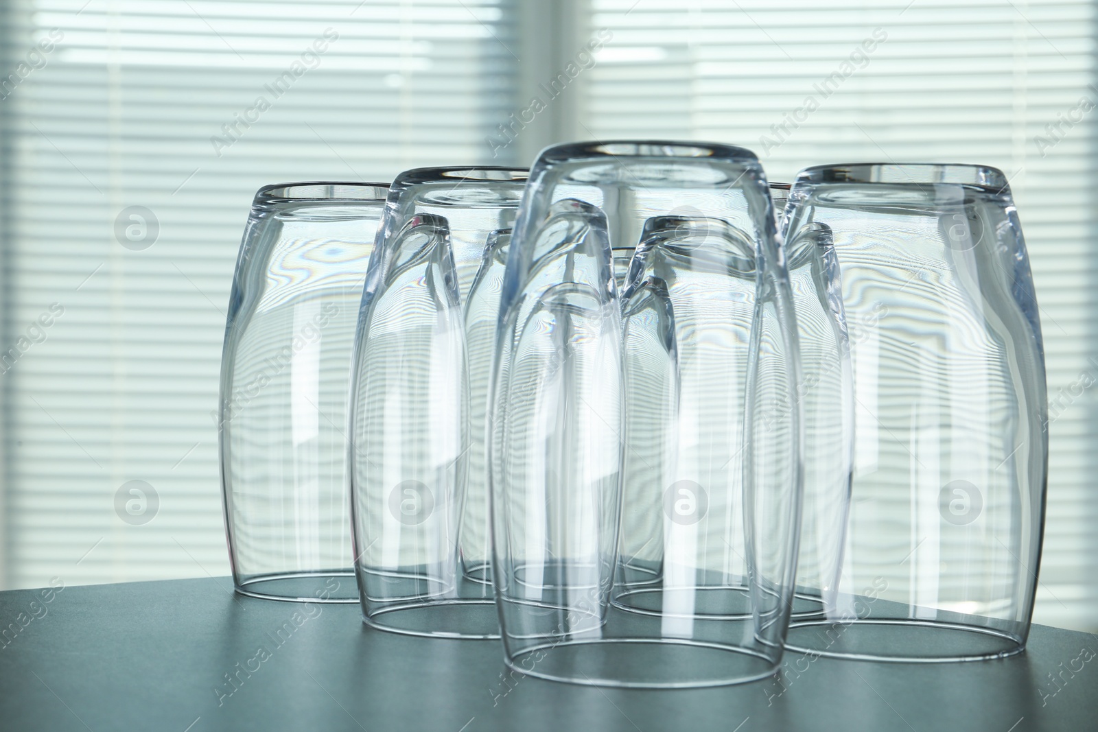 Photo of Empty glasses on grey table against blurred background, closeup