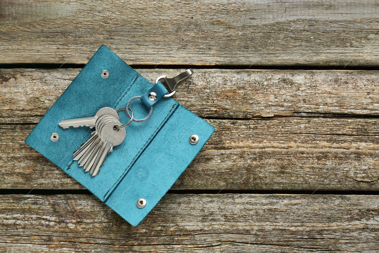 Photo of Open leather holder with keys on old wooden table, top view. Space for text