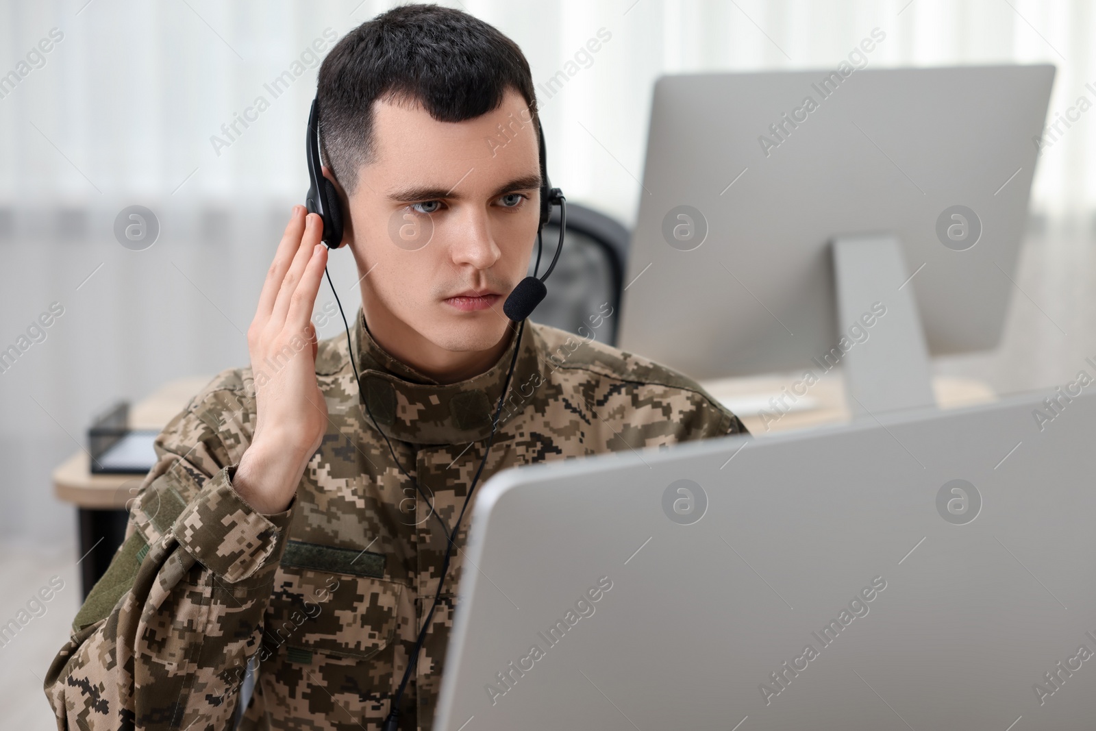 Photo of Military service. Young soldier in headphones working in office