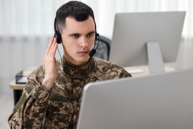 Military service. Young soldier in headphones working in office