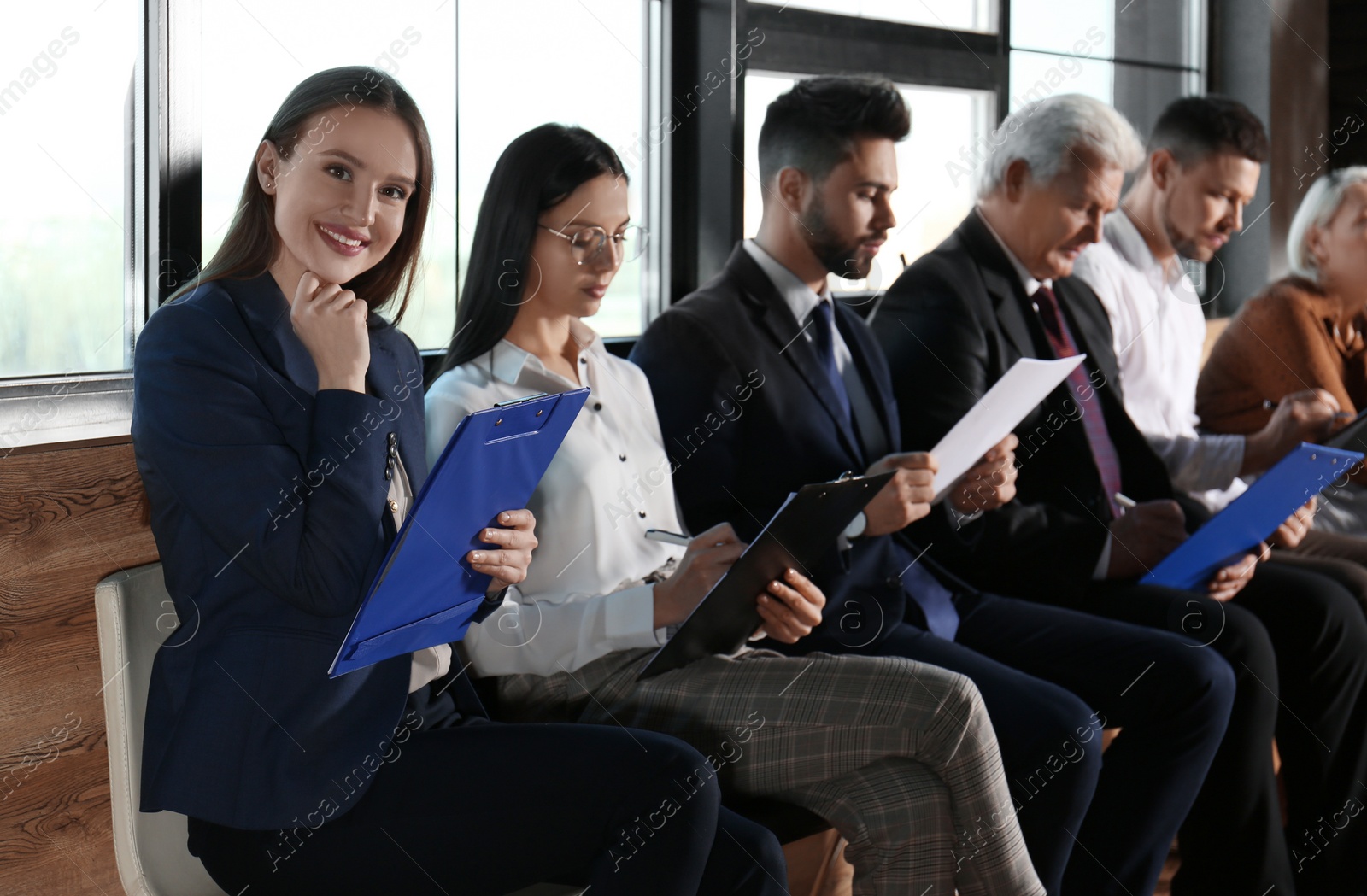 Photo of Young woman with clipboard waiting for job interview in office hall