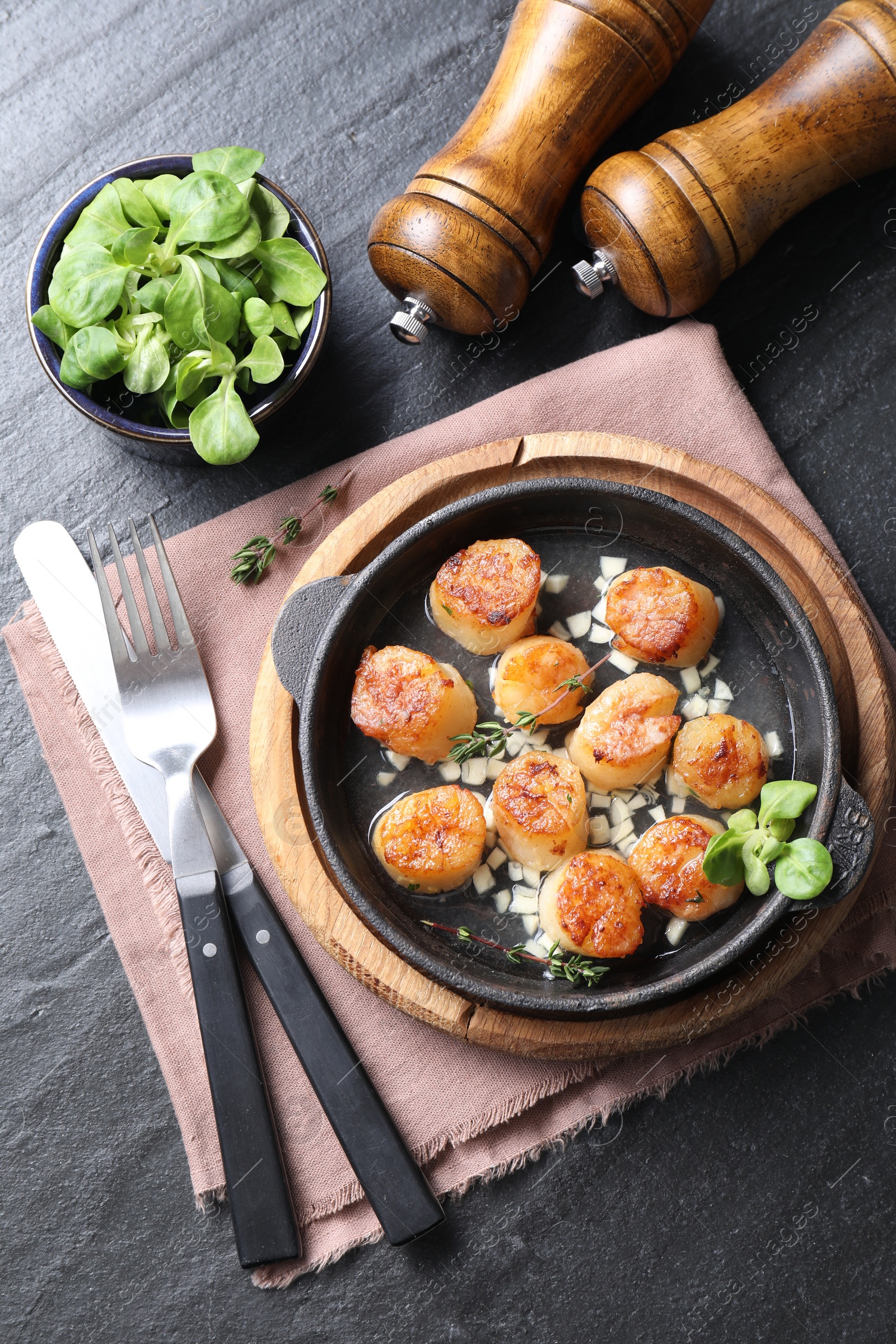 Photo of Delicious fried scallops in dish served on dark gray textured table, flat lay