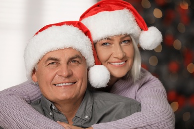 Happy mature couple in Santa hats at home. Christmas celebration