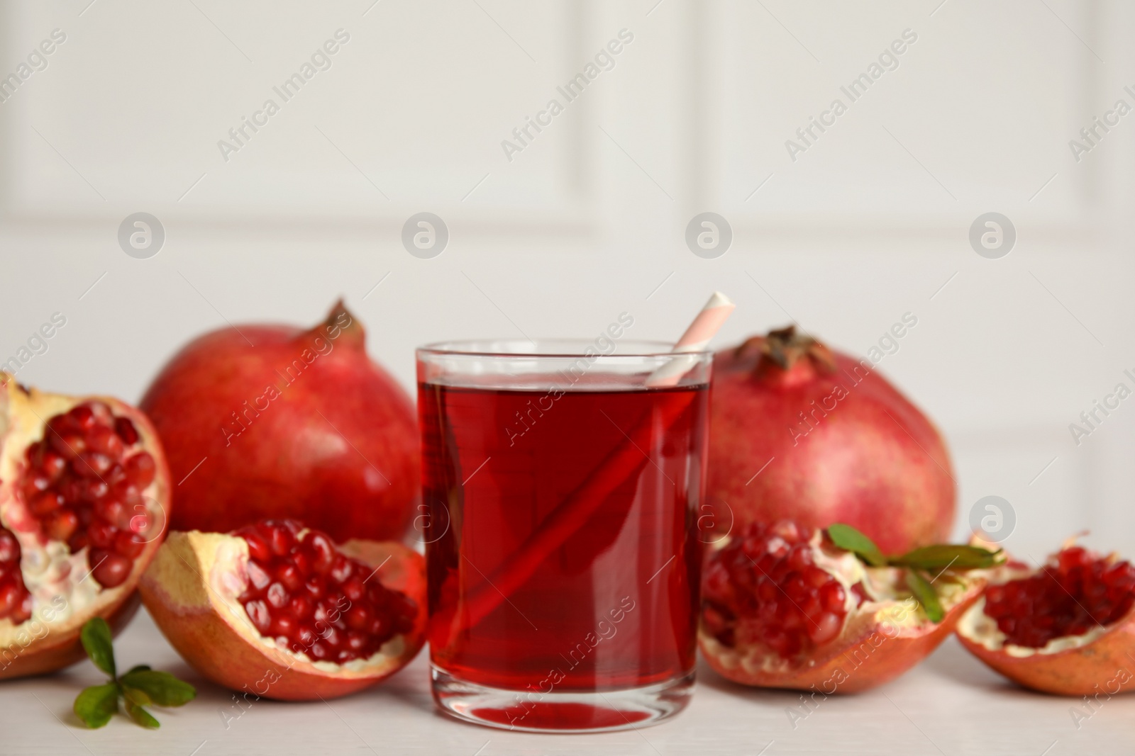 Photo of Glass of pomegranate juice and fresh fruits on white table