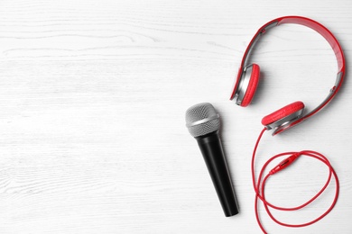 Photo of Headphones, microphone and space for text on white wooden background, top view