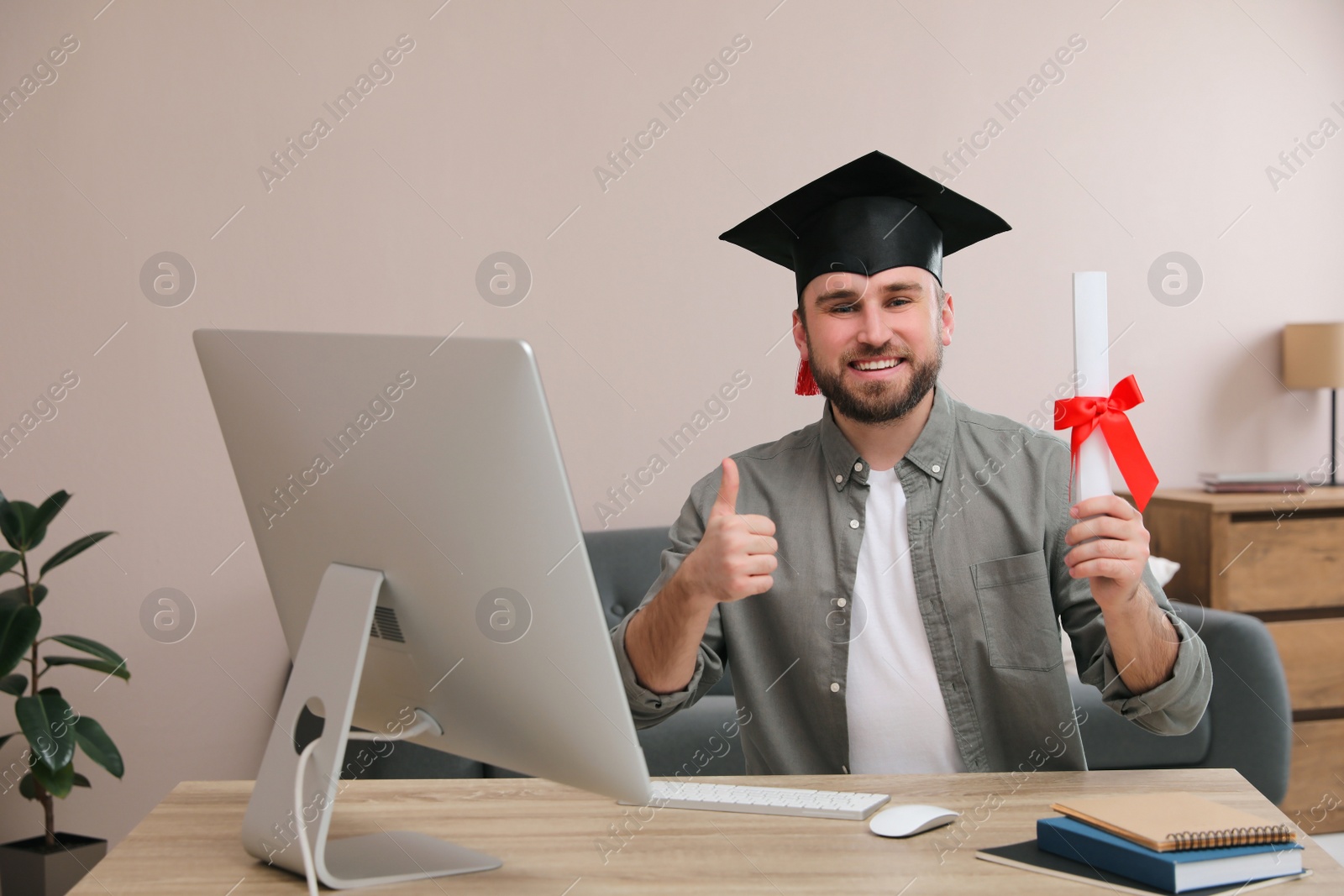 Photo of Happy student with graduation hat and diploma at workplace in office