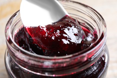 Spoon with berry jam in jar, closeup