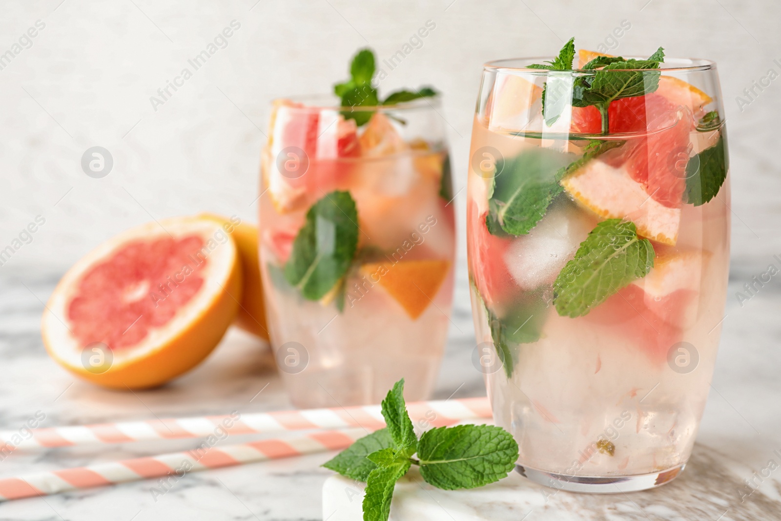 Photo of Glasses of refreshing drink with grapefruit and mint on marble table, space for text