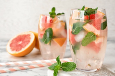 Photo of Glasses of refreshing drink with grapefruit and mint on marble table, space for text