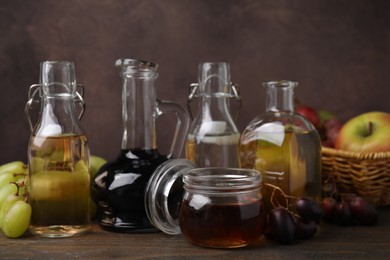 Photo of Different types of vinegar and fresh fruits on wooden table