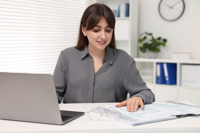 Smiling secretary doing paperwork at table in office