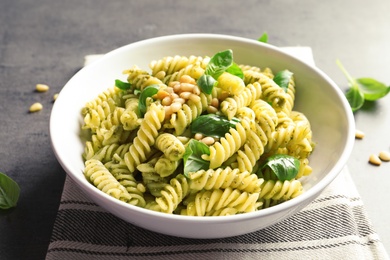 Plate with delicious basil pesto pasta on gray table