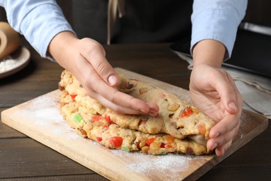 Photo of Woman making Stollen with candied fruits and raisins on wooden board at table, closeup