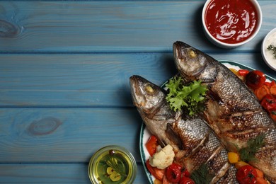 Photo of Plate with delicious baked sea bass fish and vegetables on light blue table, flat lay. Space for text