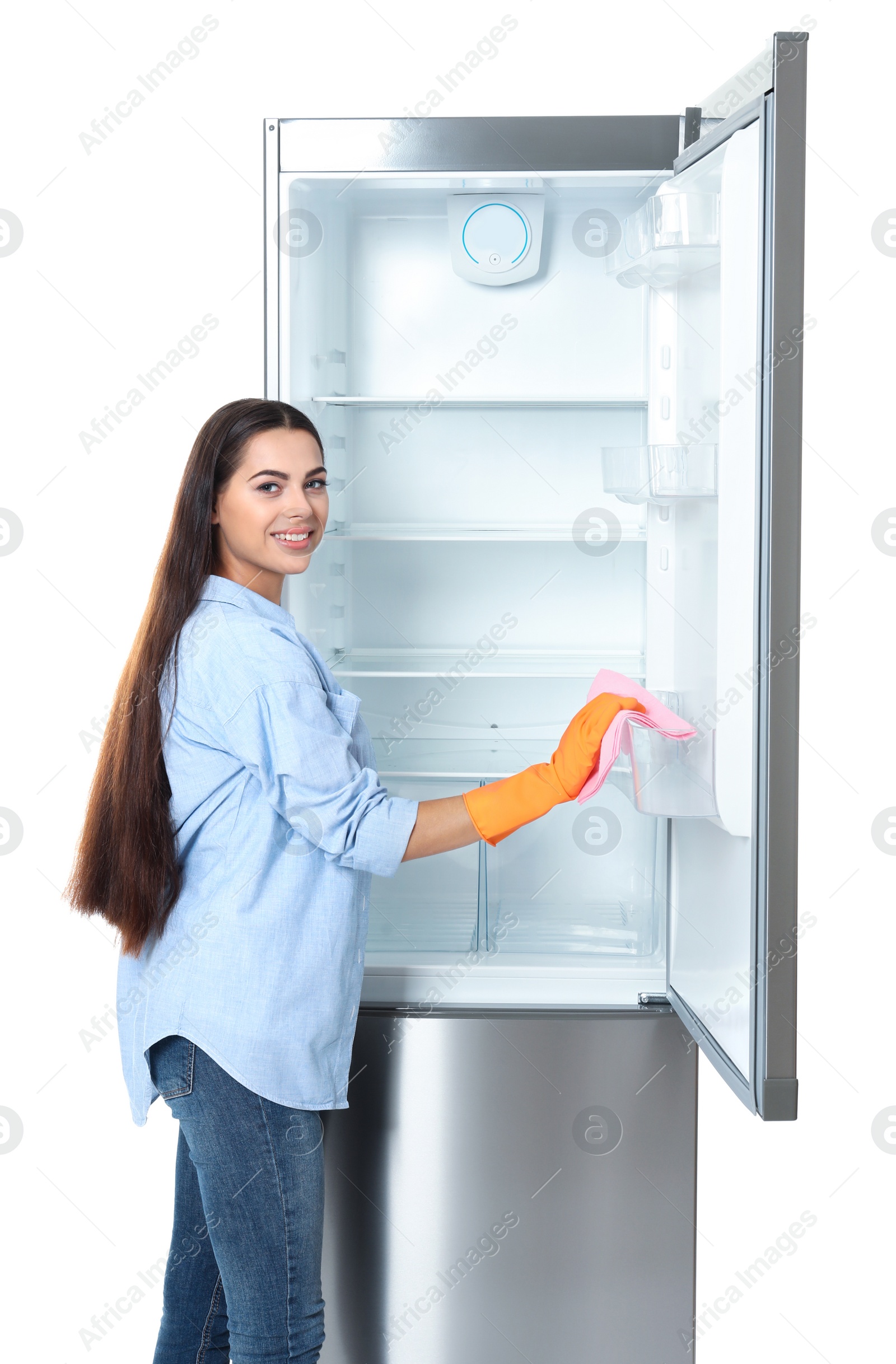 Photo of Young woman cleaning refrigerator with rag on white background