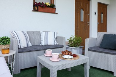 Outdoor breakfast with tea and croissants on rattan table on terrace