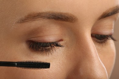 Photo of Woman applying mascara onto eyelashes, closeup view