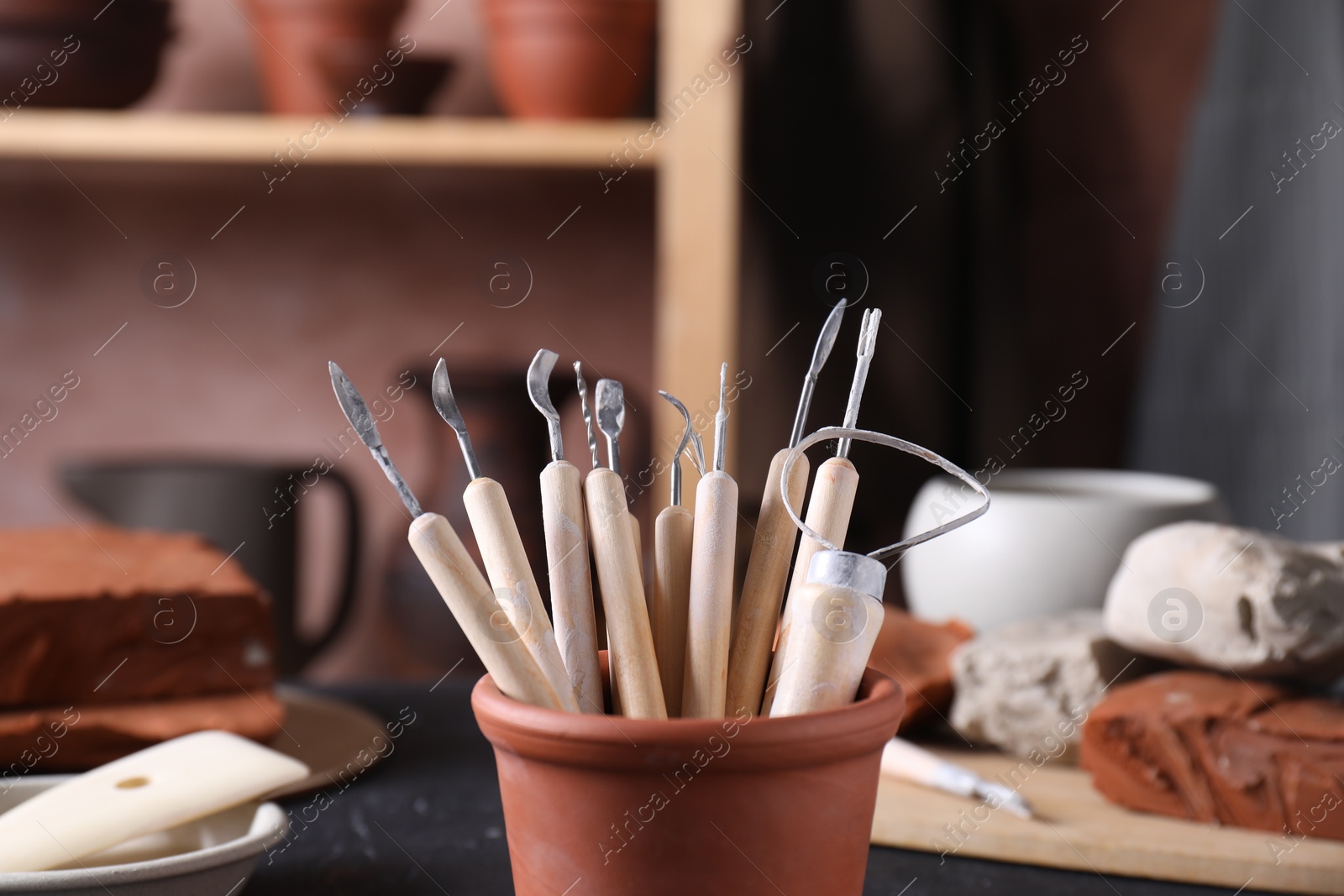 Photo of Set of different clay crafting tools on table in workshop, closeup