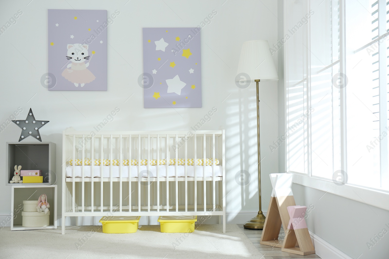 Photo of Stylish baby room interior with crib and cute pictures on wall