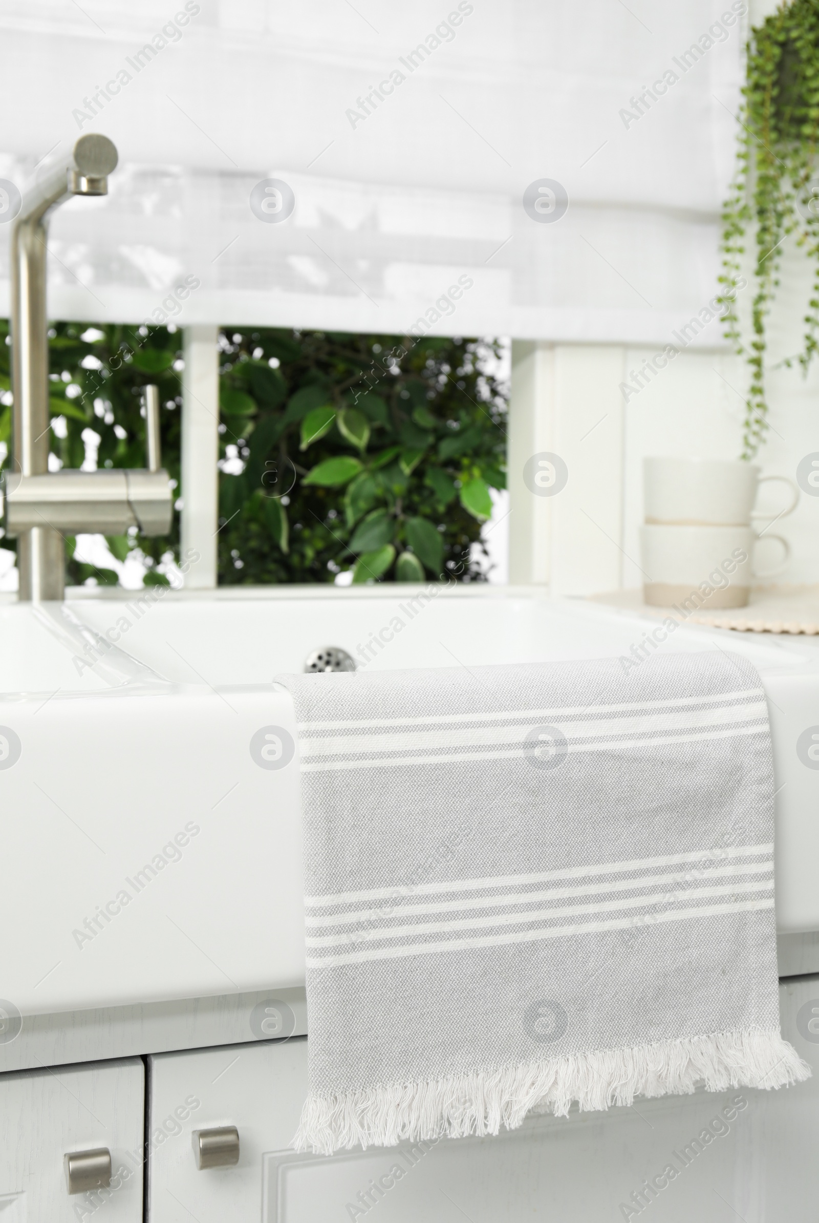 Photo of Clean towel hanging on white sink in kitchen