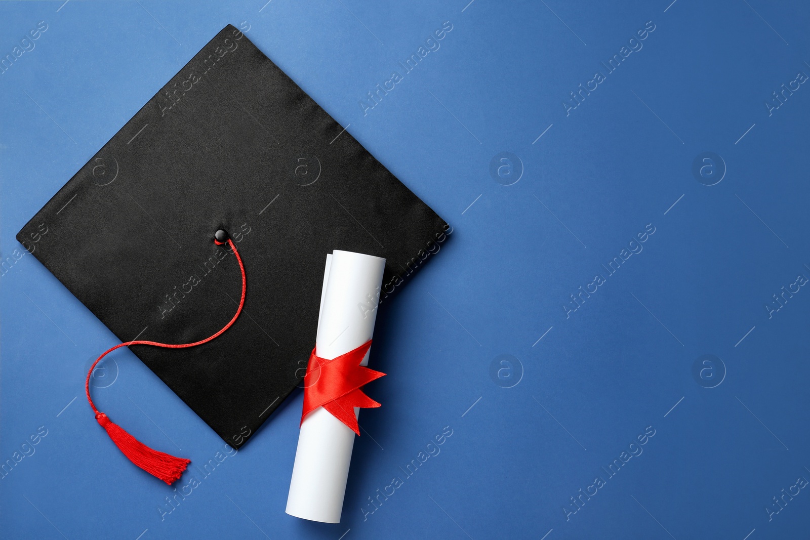 Photo of Graduation hat and diploma on blue background, top view. Space for text