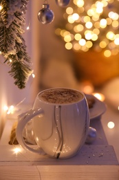 Photo of Cup of tasty hot drink and Christmas tree branch indoors. Space for text