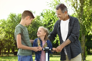 Photo of Male pensioner with grandchildren in park on sunny day