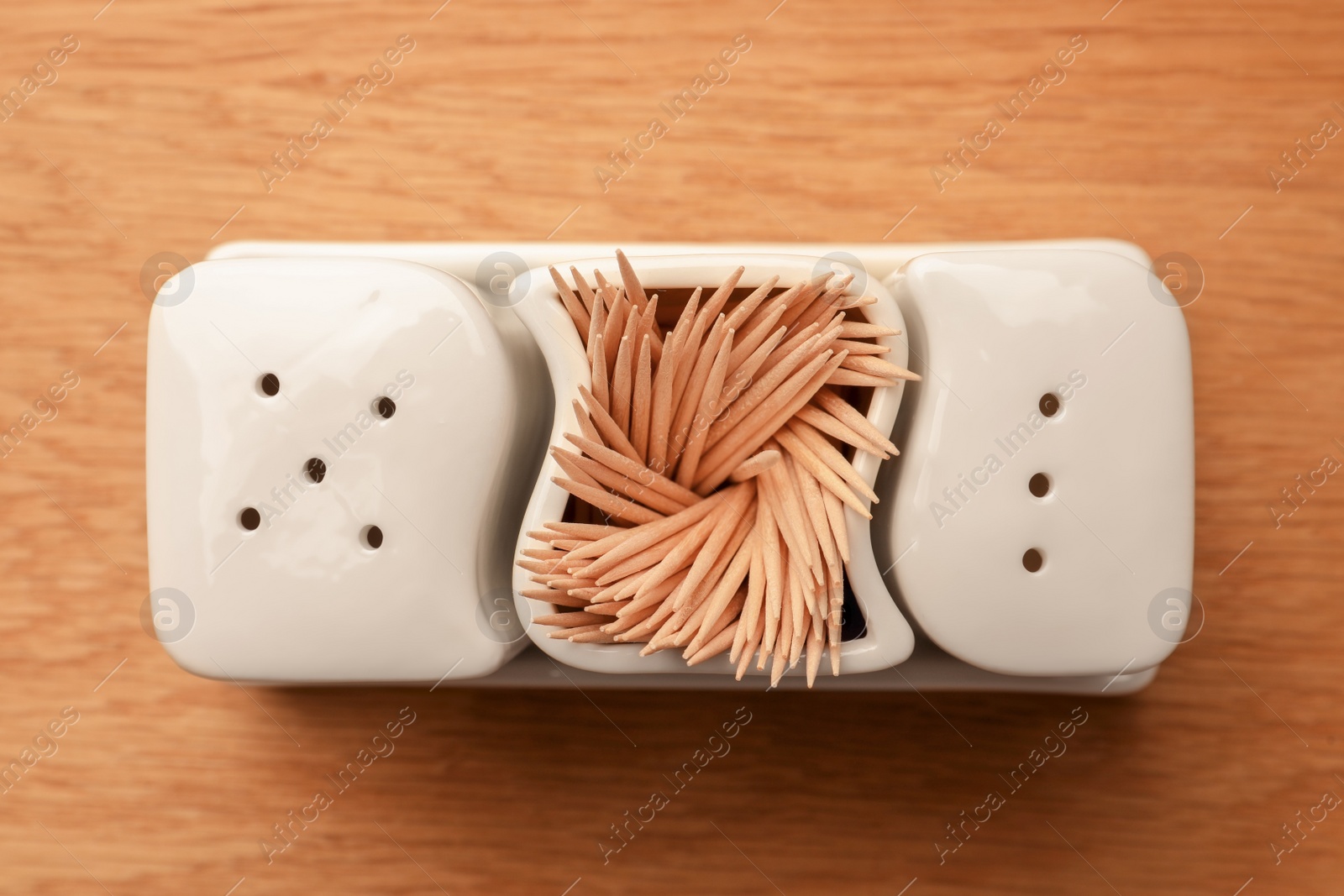 Photo of Holder with salt, pepper and toothpicks on wooden table, top view