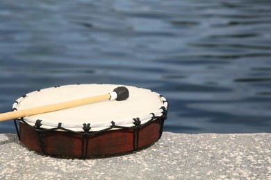 Drum and drumstick near sea, space for text. Percussion musical instrument