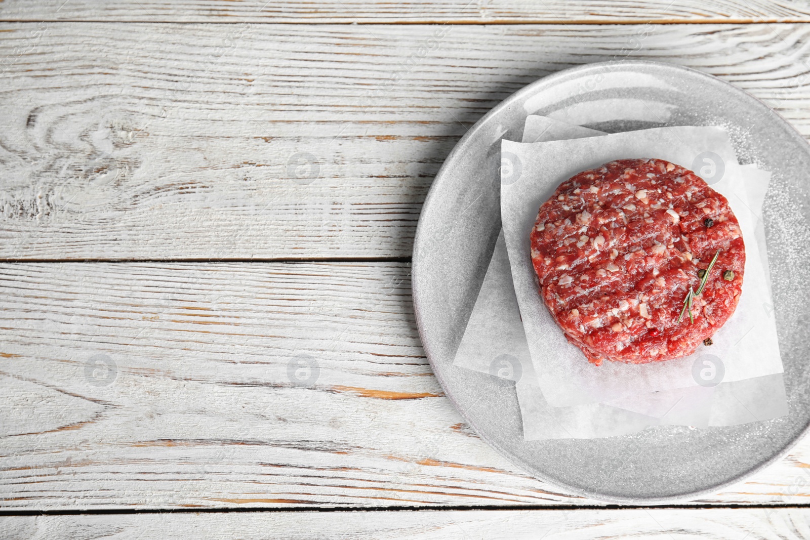 Photo of Raw meat cutlet for burger on white wooden table, top view. Space for text