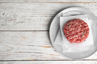 Raw meat cutlet for burger on white wooden table, top view. Space for text