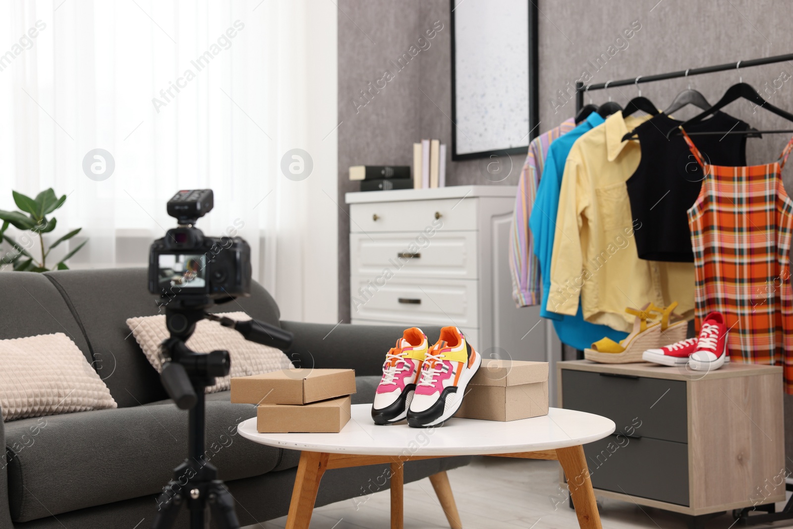 Photo of Fashion blogger's workplace. Shoes, clothes, camera and stylish furniture indoors