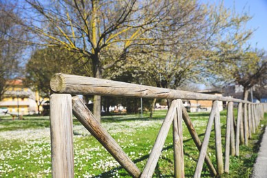Rustic wooden fence in beautiful city park on sunny spring day