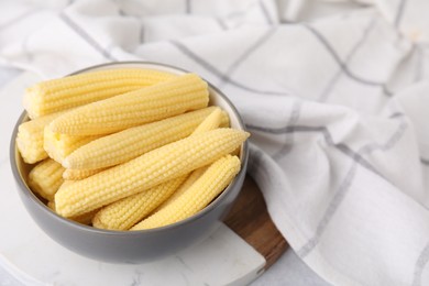 Photo of Tasty fresh yellow baby corns in bowl on white table, space for text